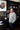 Man standing in a room with dark walls, artwork, and shelves.